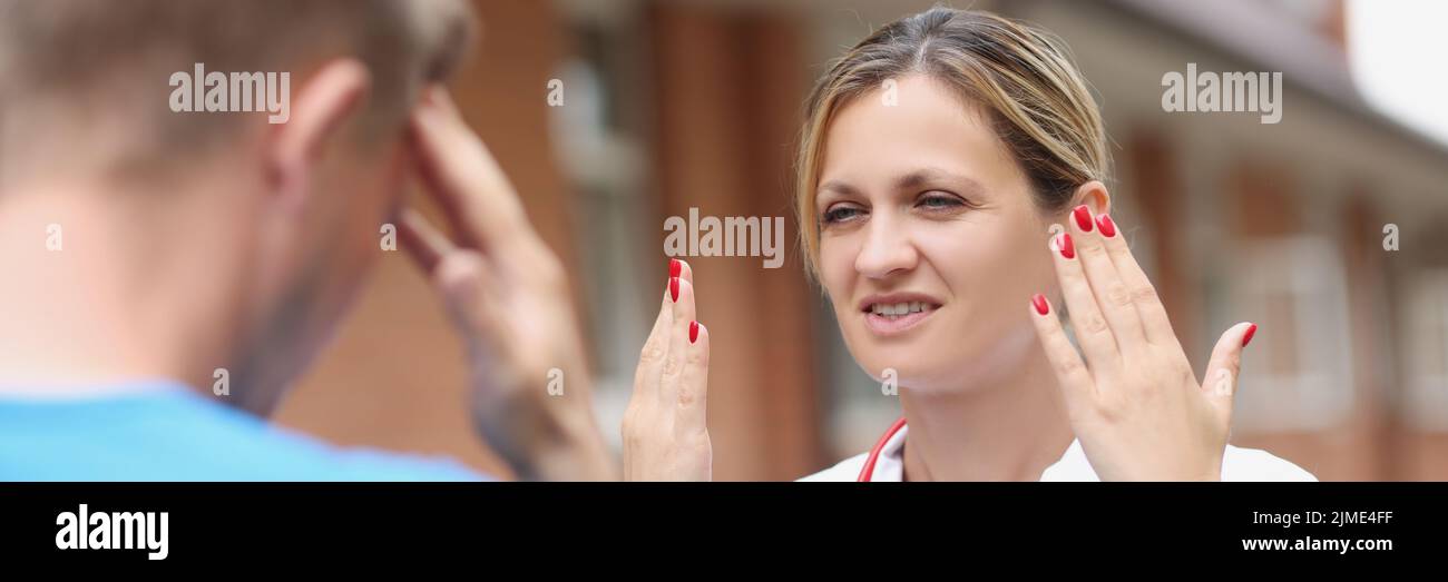 Una doctora habla con un hombre en la calle, de cerca Foto de stock