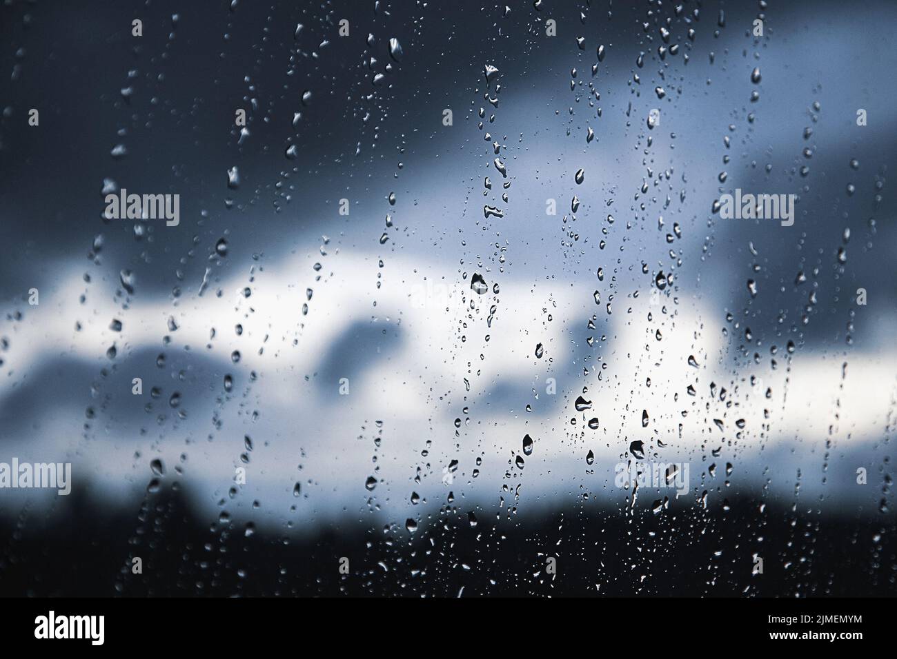 Gotas de lluvia en el panel de la ventana. Degradado negro, gris y blanco sobre fondo borroso. Nublado tiempo lluvioso fuera de la ventana. Refrigeración Foto de stock