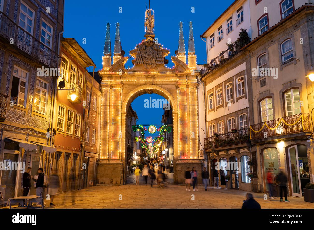 Braga, PORTUGAL - 25 de junio de 2022: Gente alrededor del Arco da Porta Nova iluminado en Braga al atardecer / hora azul. Foto de stock