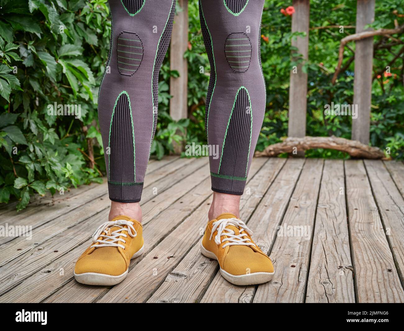piernas masculinas en mangas de compresión que promueven la circulación sanguínea y el flujo de oxígeno para aliviar el dolor de rodilla y pantorrilla Foto de stock
