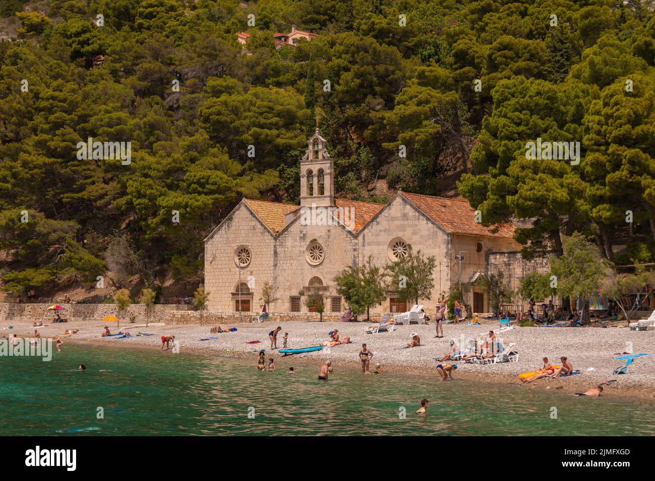 KOMIZA, VIS, CROACIA, EUROPA - La gente disfruta de la playa en la ciudad costera de Komiza, en la isla de Vis, en el mar Adriático. Foto de stock