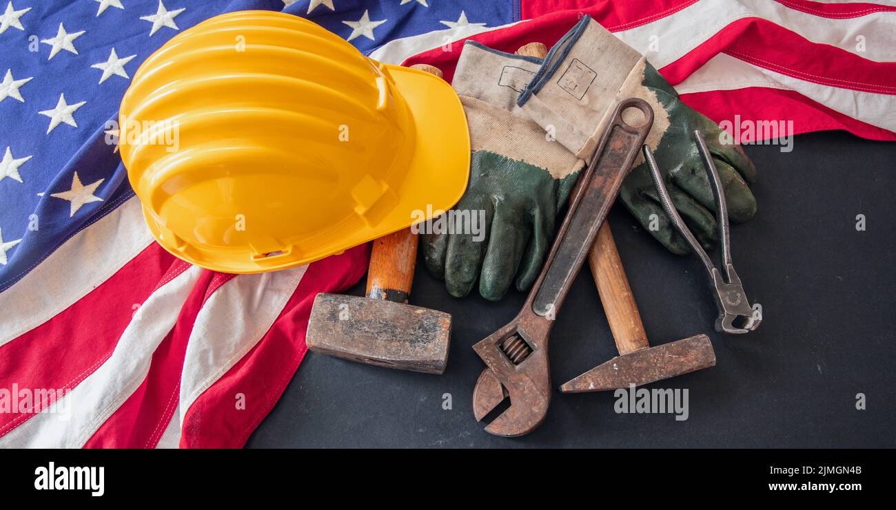 Concepto de Día del Trabajo. Bandera americana y herramientas de construcción sobre fondo oscuro, sobre la vista. Celebración de las fiestas federales de los Estados Unidos Foto de stock