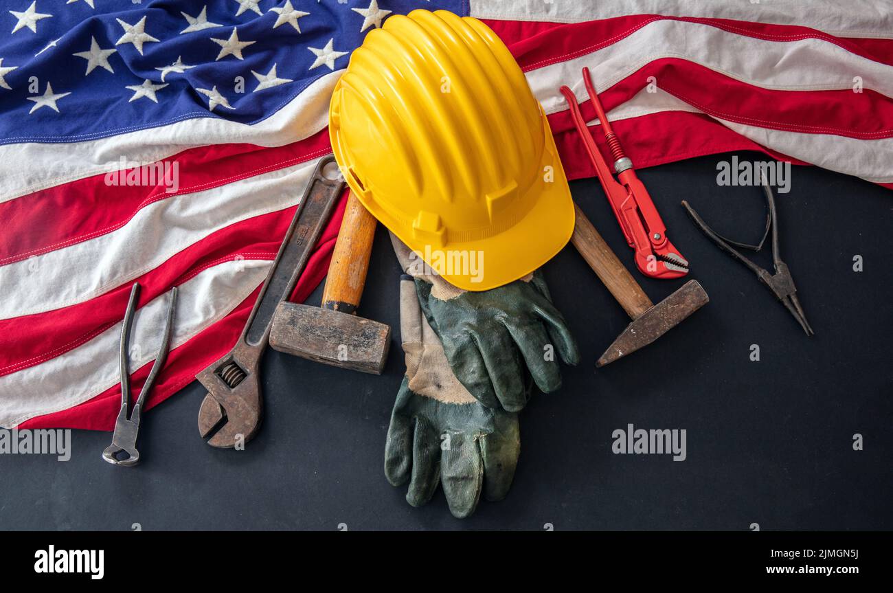 Concepto de Día del Trabajo. Bandera americana y herramientas de construcción sobre fondo oscuro, sobre la vista. Celebración de vacaciones en Estados Unidos Foto de stock