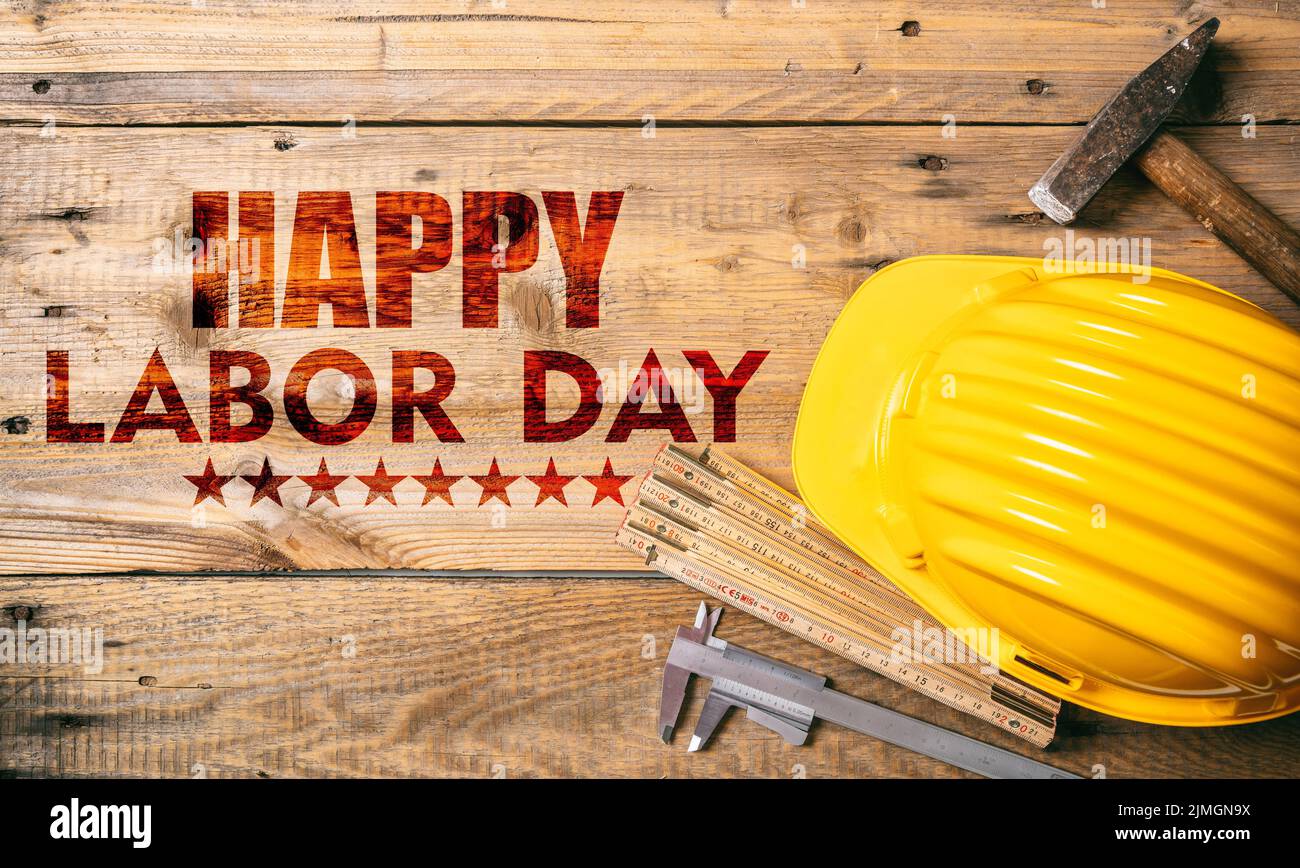 Happy Labor Day texto y herramientas de construcción en una mesa de madera, vista superior. Celebración de las fiestas de Estados Unidos Foto de stock