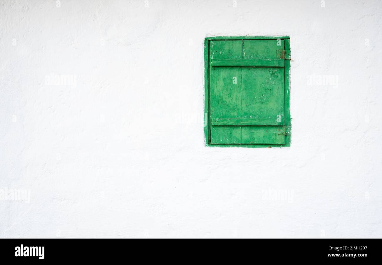 Una ventana verde en una pared blanca Foto de stock