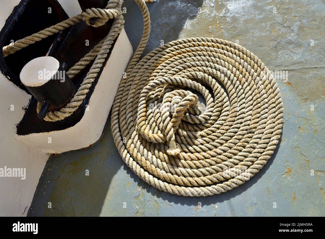 Cuerda enrollada y tacos en la cubierta oxidada del barco Foto de stock