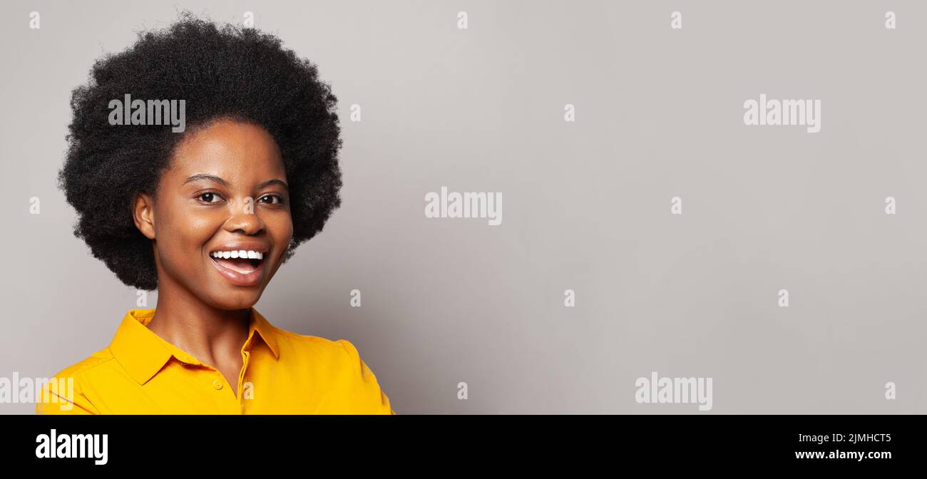 Feliz joven mujer negra sonriendo sobre fondo blanco de la pared Foto de stock