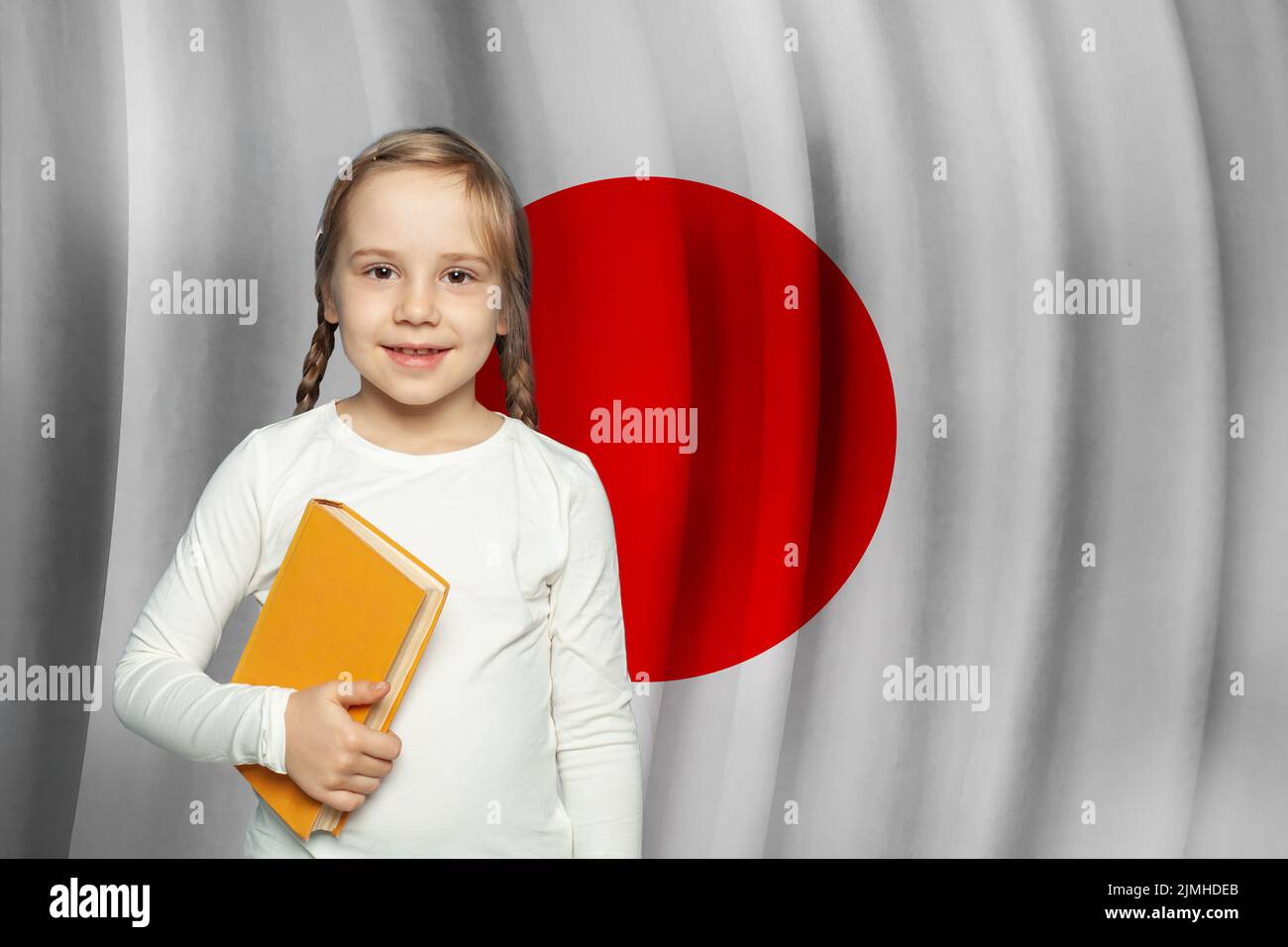 Niña pequeña estudiante en el fondo de la bandera japonesa. Educación y escuela en Japón Concepto Foto de stock