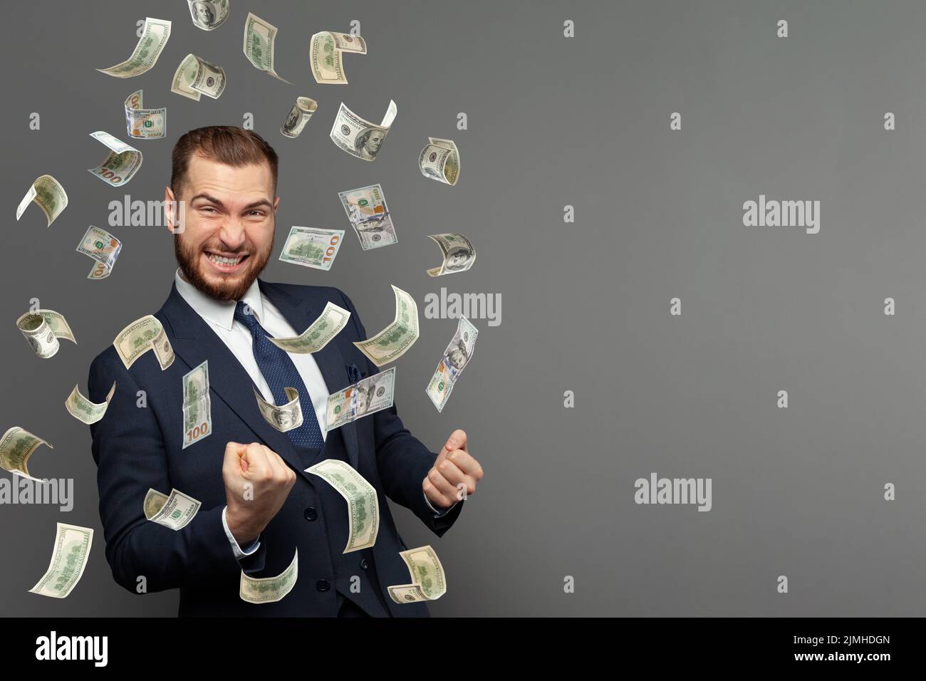 Retrato de hombre feliz gritando bajo la lluvia del dinero cayendo billetes de dólares aislados sobre fondo gris con espacio de copia. Libertad financiera co Foto de stock