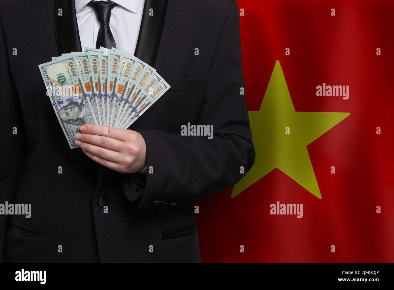 100 Billetes en dólares de los EE.UU. Billetes en mano contra bandera de Vietnam antecedentes Foto de stock