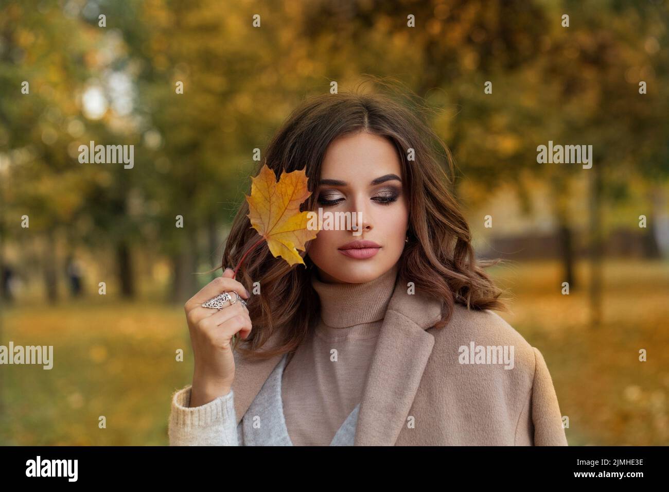 Retrato de mujer Atumn. Modelo hermoso sostiene el arce de otoño las hojas al aire libre Foto de stock