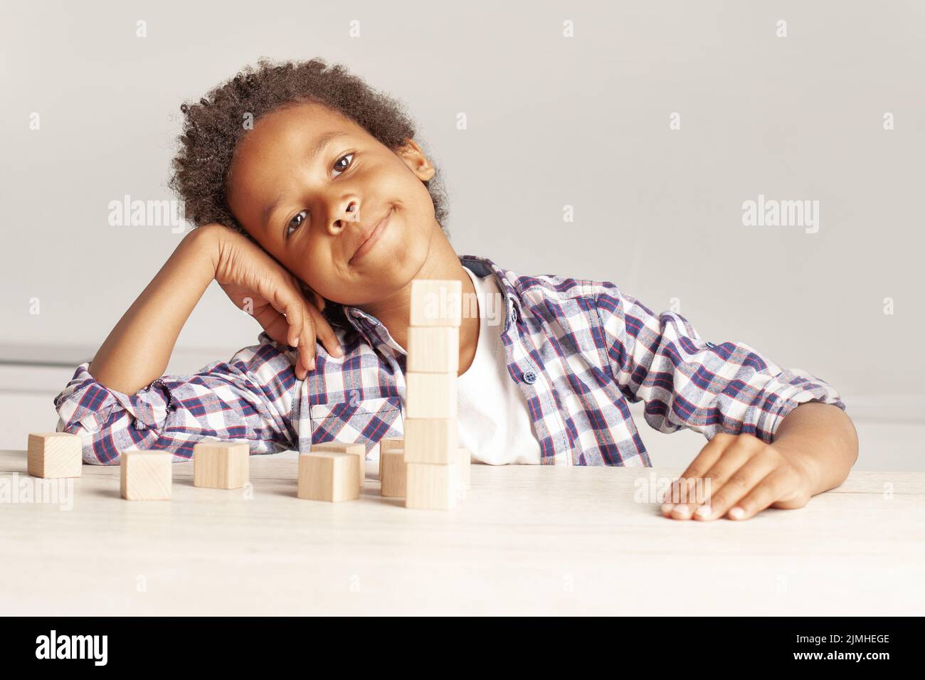 Curioso niño afroamericano con cubos de madera sobre fondo blanco Foto de stock