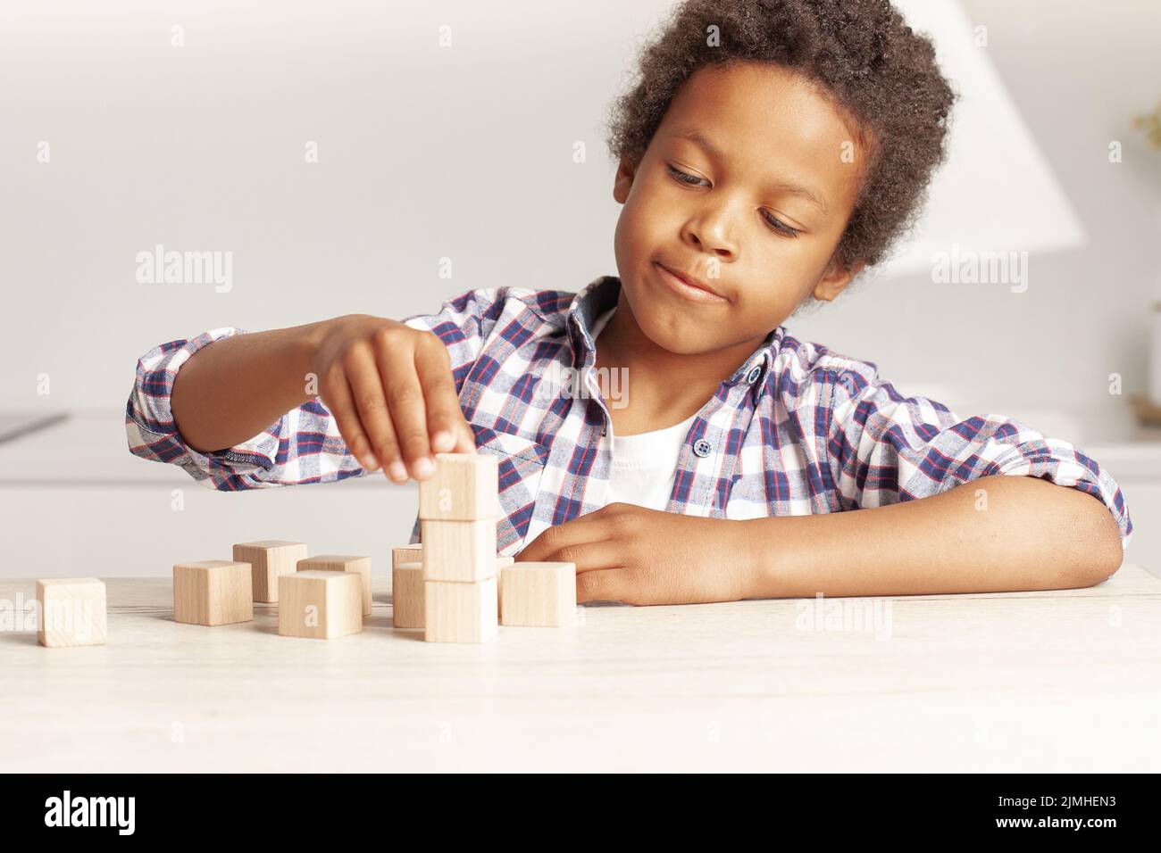 Niño afroamericano niño pequeño eligiendo cubo de bloque de madera juguete apilado sin gráficos Foto de stock
