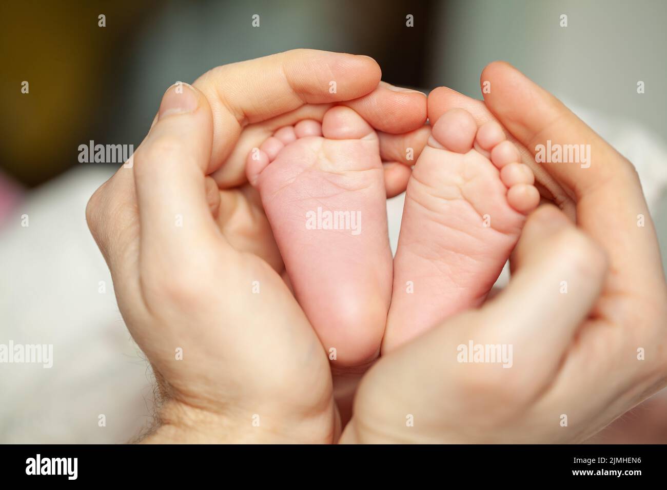 Las manos de papá tocan las piernas de su adorable hija recién nacida Foto de stock