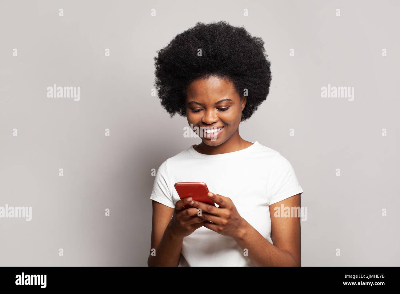 Aplicación increíble. Mujer negra feliz con smartphone sobre fondo blanco Foto de stock