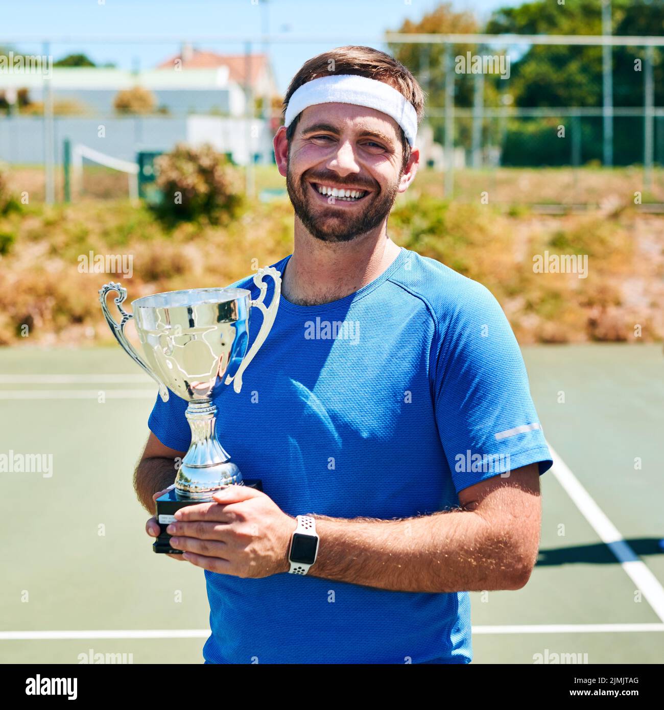 Me lo he ganado. Retrato recortado de un joven guapo sosteniendo un trofeo después de ganar un partido de tenis durante el día. Foto de stock