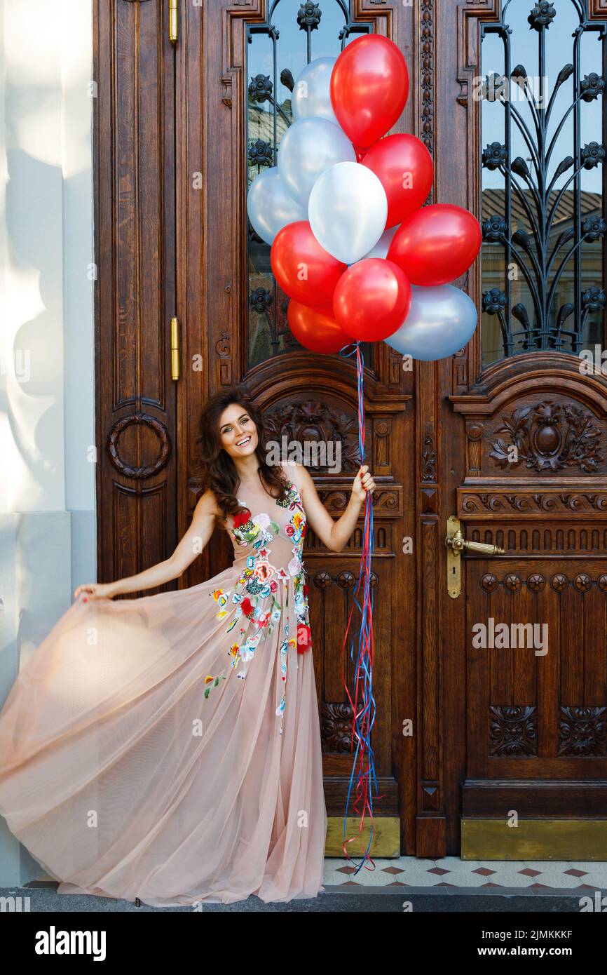 Mujer con un hermoso vestido con muchos globos de colores Foto de stock