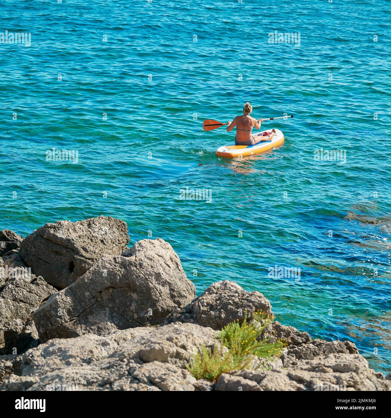 Mujer en una tabla de paddle de pie en el mar Adriático cerca de Krk en Croacia Foto de stock