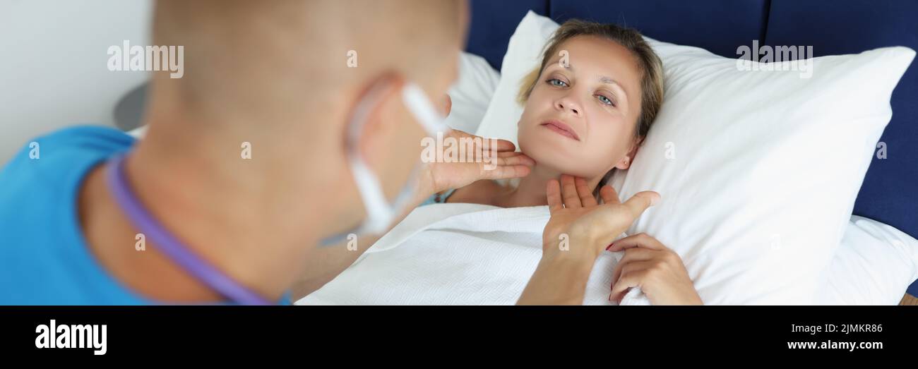 La mujer enferma yace en el hombre del médico de la cama que revisa los ganglios linfáticos Foto de stock