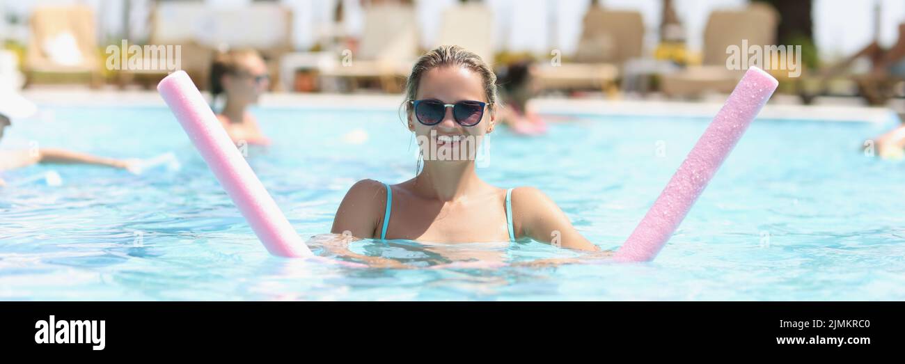 Una mujer feliz se dedica al aqua fitness en la piscina al aire libre Foto de stock