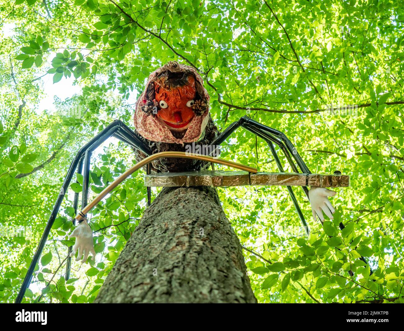 Juguete o estatua de una araña dama con un violín entre sus ocho patas. Lazo de cuerda Hágalo Gossamer telaraña en el árbol en el parque de juegos de los niños Foto de stock
