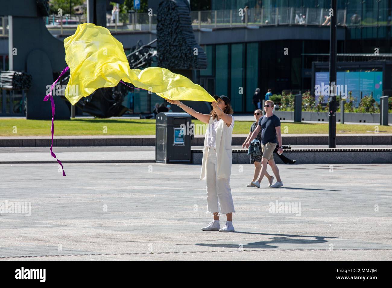 Mujer agitando un paño amarillo en la plaza Kansalaistori, Helsinki, Finlandia Foto de stock