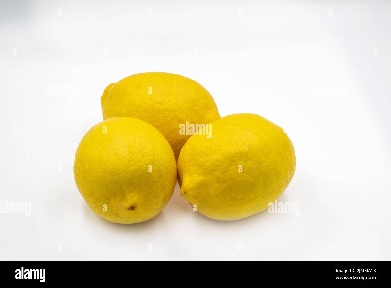Tres limones enteros frescos de primer plano contra blanco Foto de stock