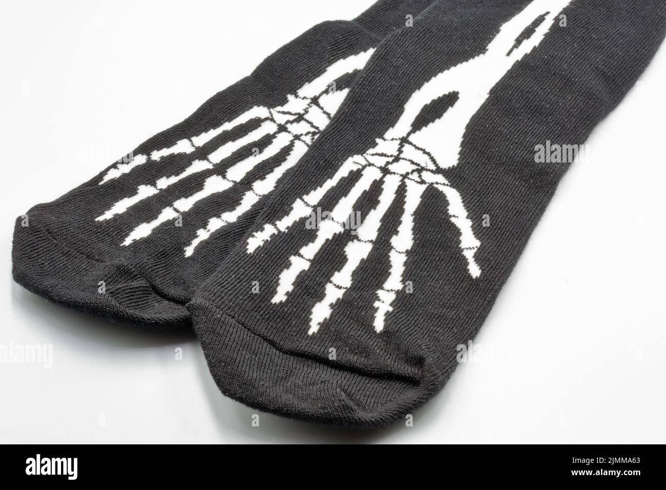 Calcetines negros con primer plano de esqueleto de mano blanco sobre blanco. Estampado de Halloween. Foto de stock
