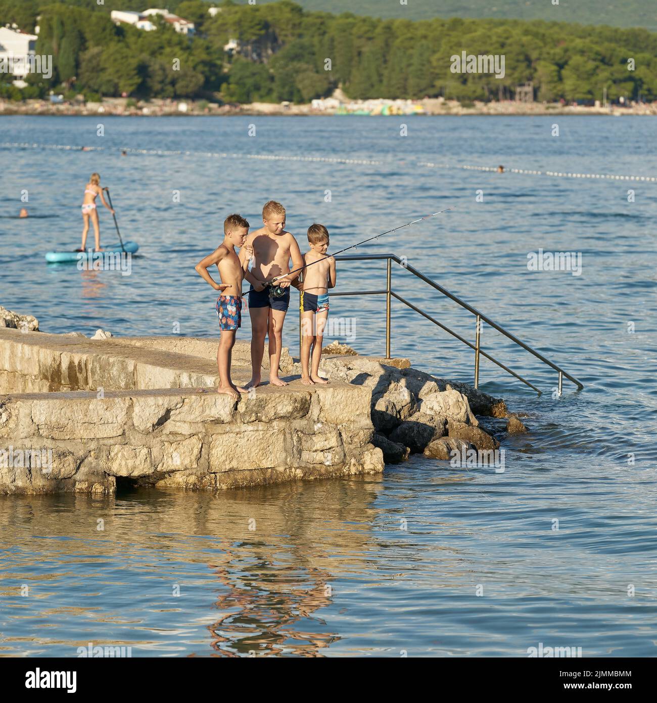 Los niños de la costa cerca de la ciudad de Krk en Croacia se divierten nadando y pescando en el Adriático Foto de stock