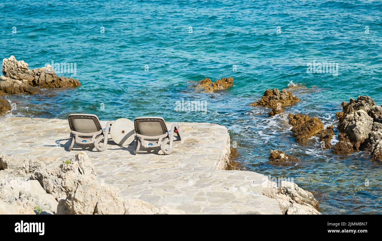 Dos tumbonas en un lugar de baño en la costa rocosa del mar Adriático cerca de Krk en Croacia Foto de stock