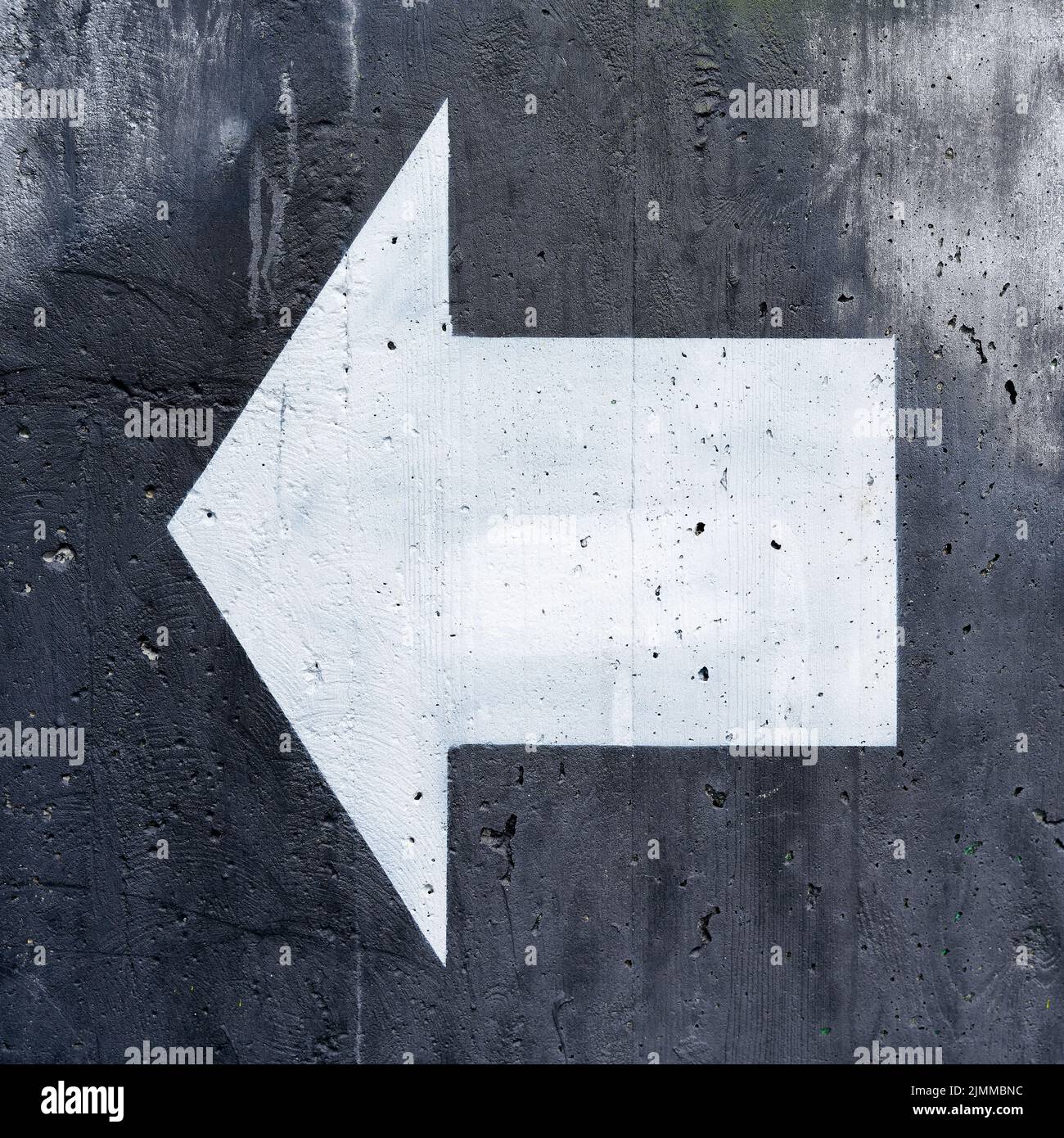 Flecha direccional blanca sobre fondo negro para orientación sobre paredes de hormigón Foto de stock