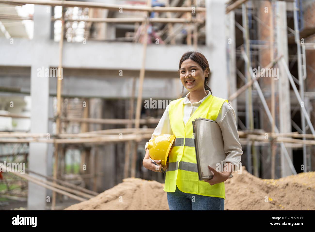Retrato de una ingeniera contratista asiática con casco que sostiene papel de impresión azul Foto de stock