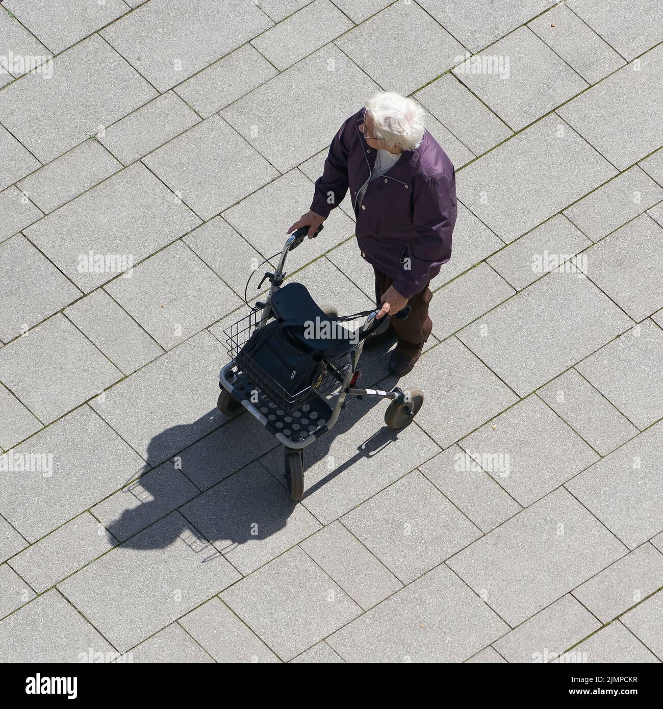Una anciana con un caminante caminando por la ciudad Foto de stock