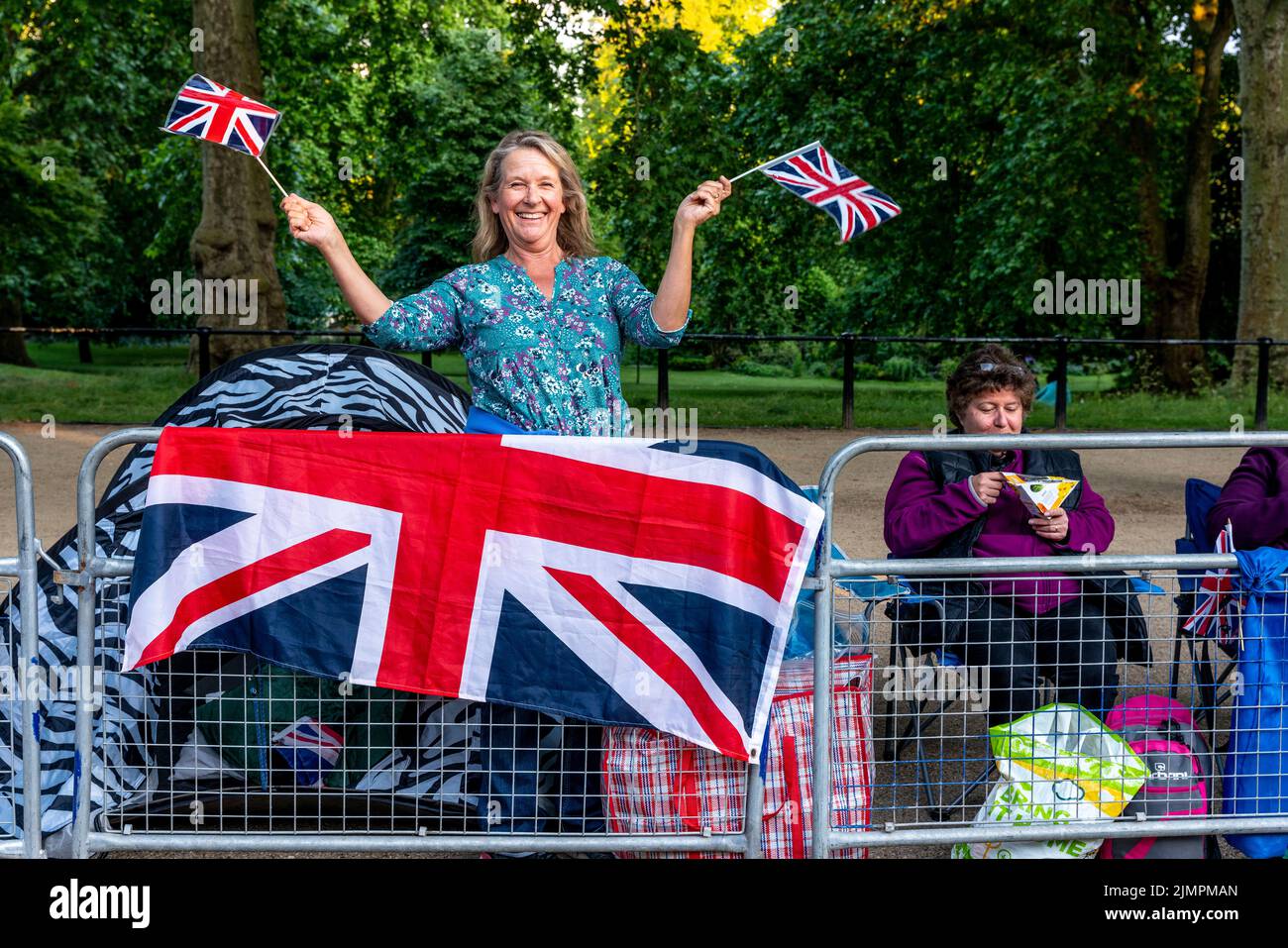 Una mujer británica ondea con Union Flags antes del desfile de cumpleaños de la reina, The Mall, Londres, Reino Unido. Foto de stock