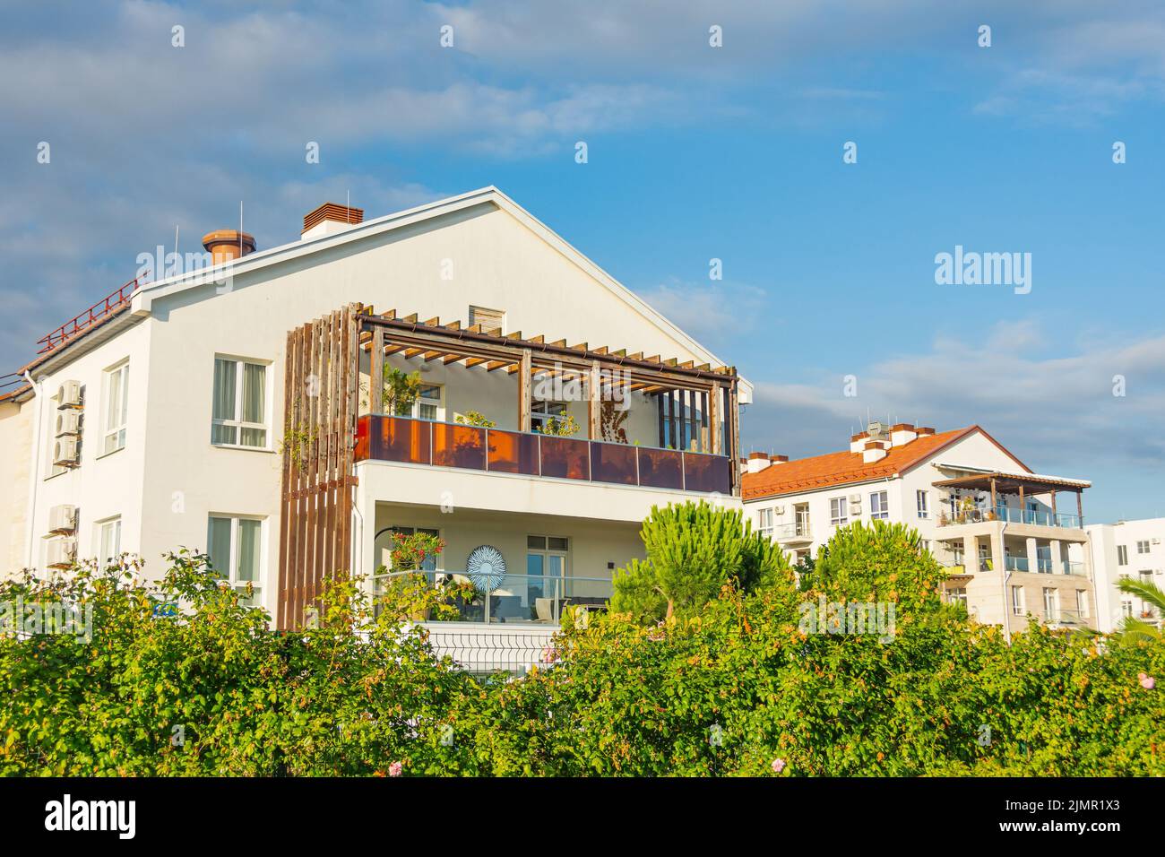 Edificios residenciales con amplios balcones y terrazas con plantas y flores en la orilla del mar Foto de stock