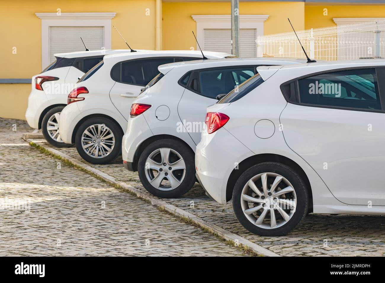 Cuatro coches blancos similares estacionados en la calle en una típica ciudad europea Foto de stock