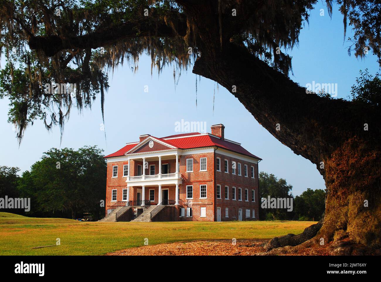 El histórico Drayton Hall es una casa de plantación en Charleston, Carolina del Sur y está enmarcado por un gran roble cubierto en musgo español Foto de stock