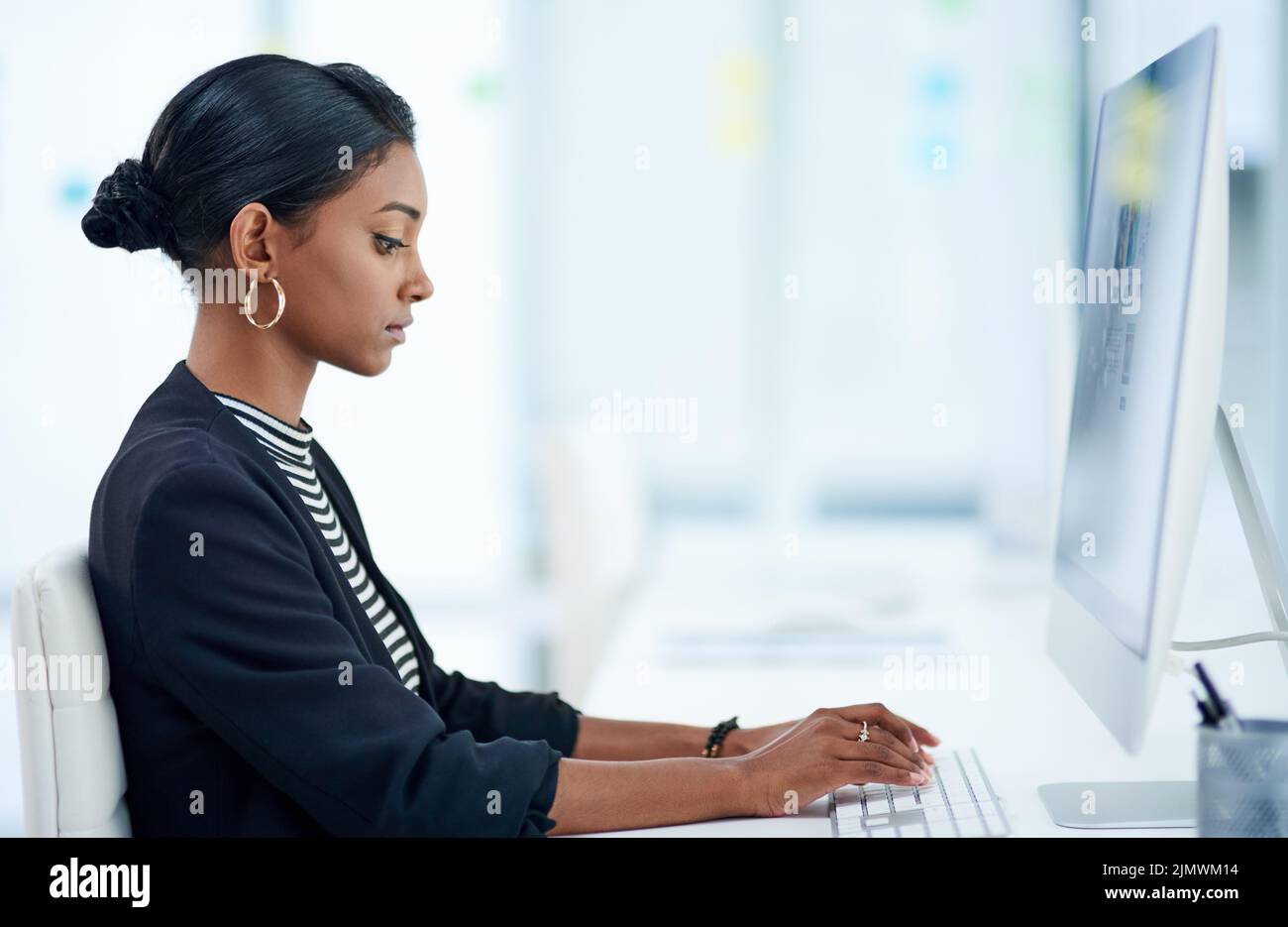 Hacer el trabajo es lo que mejor hace: Una joven empresaria atractiva que trabaja en una computadora dentro de su oficina. Foto de stock