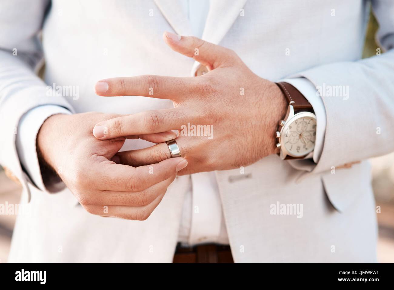 Este anillo de bodas es un símbolo de un compromiso de por vida. Un novio irreconocible ajustando su anillo el día de su boda. Foto de stock
