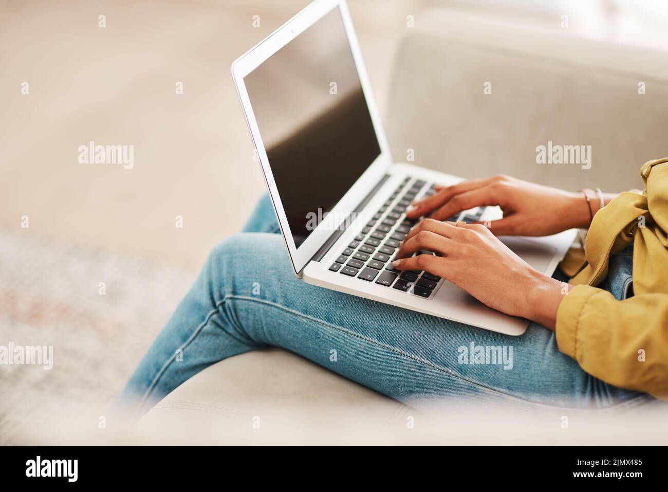 Me queda mucho por hacer. Una mujer de negocios irreconocible sentada en su sofá y blogging desde su portátil mientras está en casa. Foto de stock