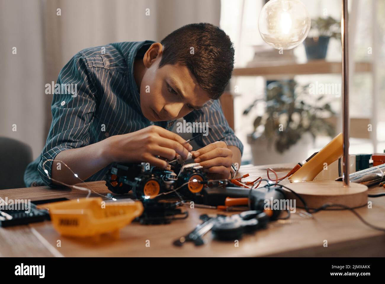 El foco es su aliado más grande en este campo. Un muchacho joven hermoso que construye un coche robótico del juguete en el país. Foto de stock