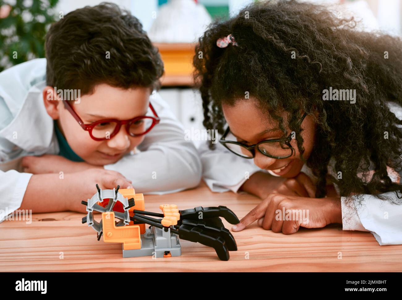 Vamos a ver si funciona. Un adorable niño y niña construyendo un robot en clase de ciencias en la escuela. Foto de stock