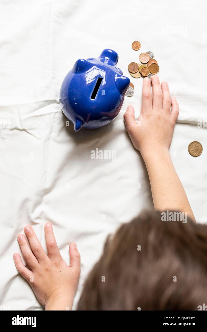 Niño de la vista superior contando su dinero de banco piggy Foto de stock