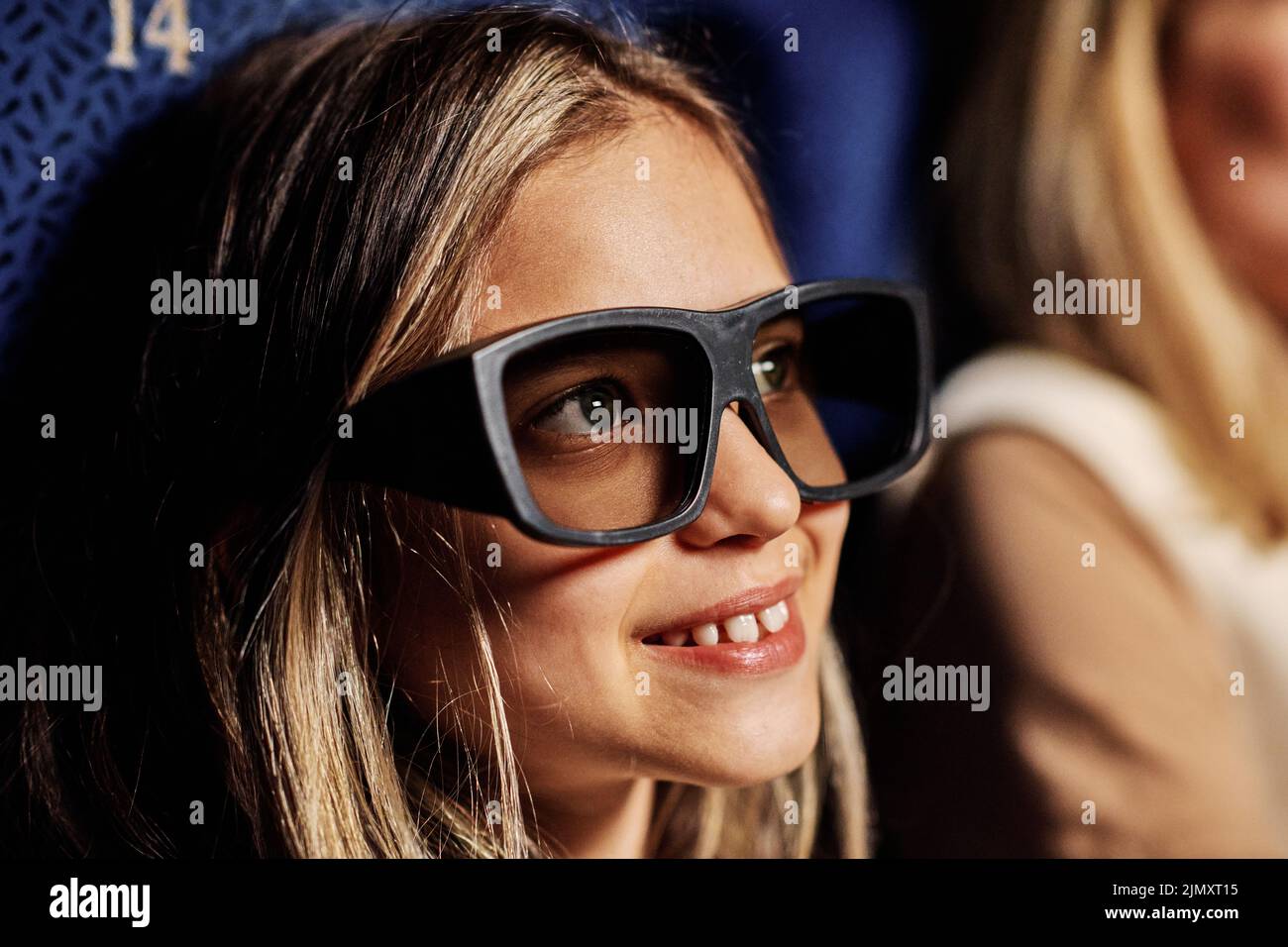 Retrato de un primer plano de una niña preadolescente caucásica con gafas 3D polarizadas que disfruta viendo una película en el cine Foto de stock
