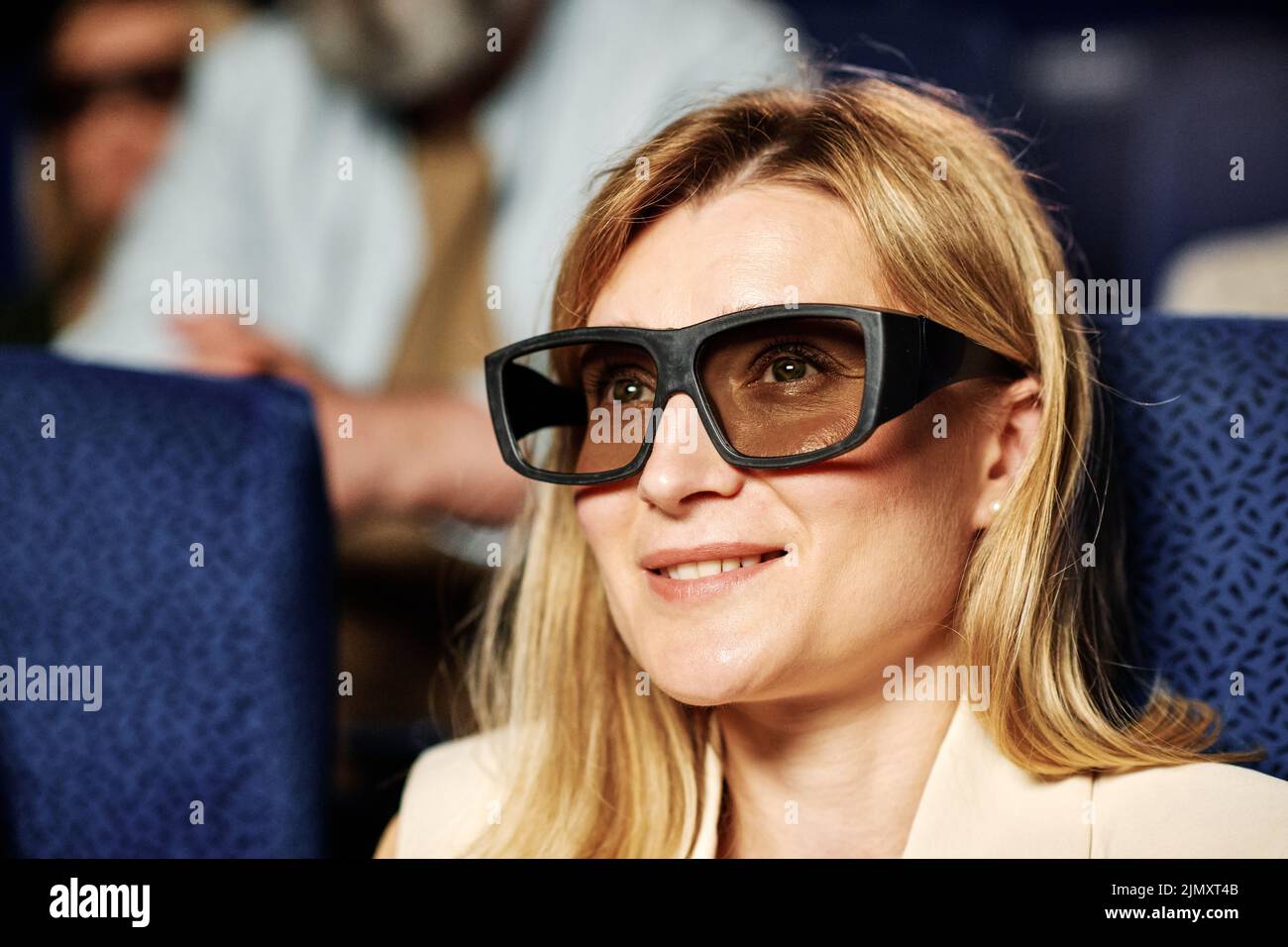 Primer plano de mujer caucásica con pelo ciego con gafas 3D polarizadas viendo una película en un cine Foto de stock