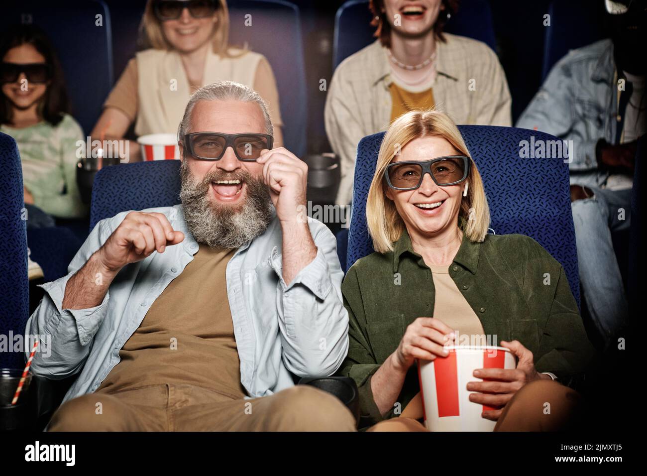Un hombre y una mujer caucasianos maduros con gafas 3D divirtiéndose viendo una película de comedia en el cine Foto de stock