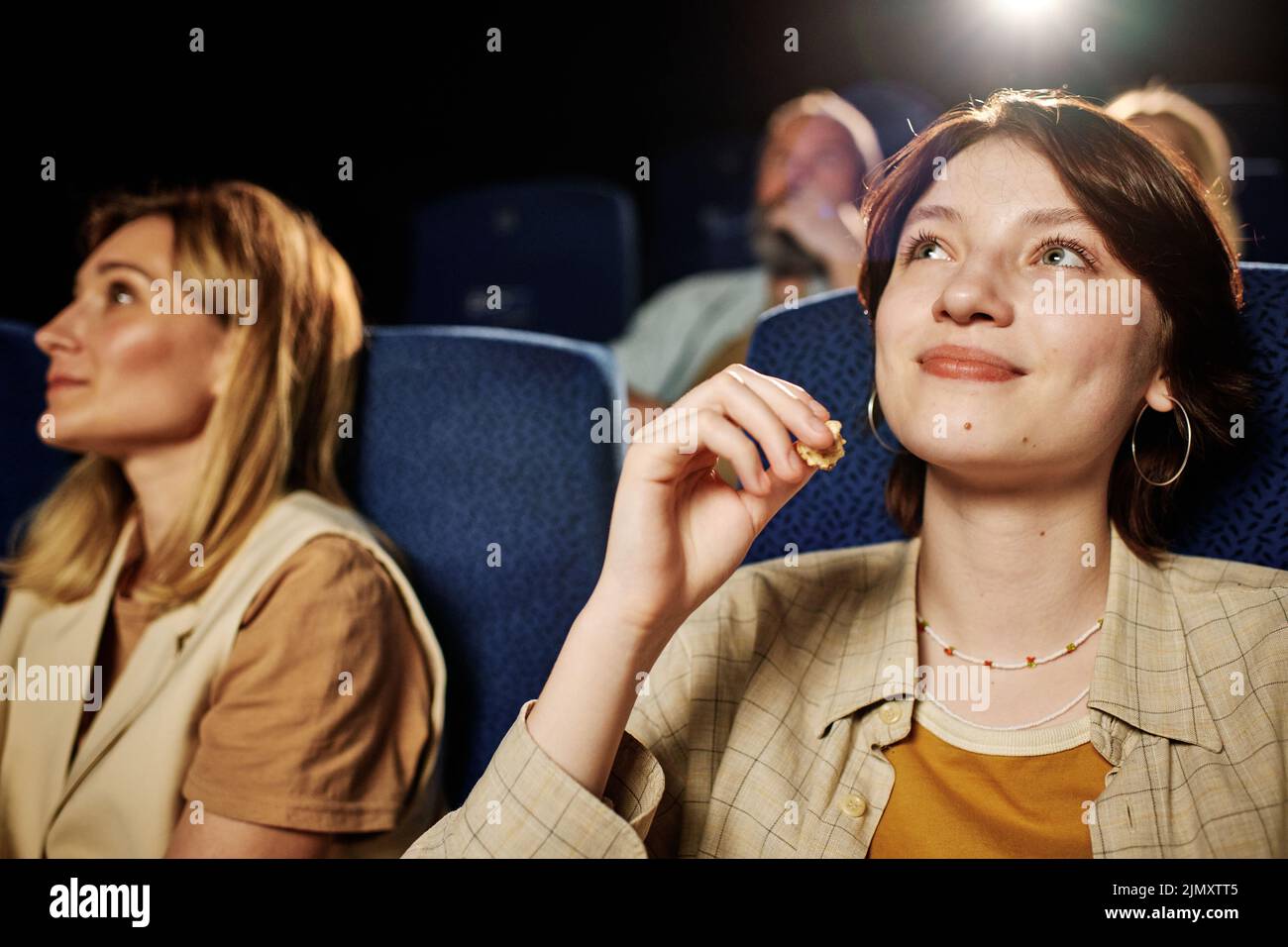 Disparo selectivo de enfoque de la joven mujer caucásica del gen Z disfrutando de una buena película y palomitas de maíz en el cine Foto de stock