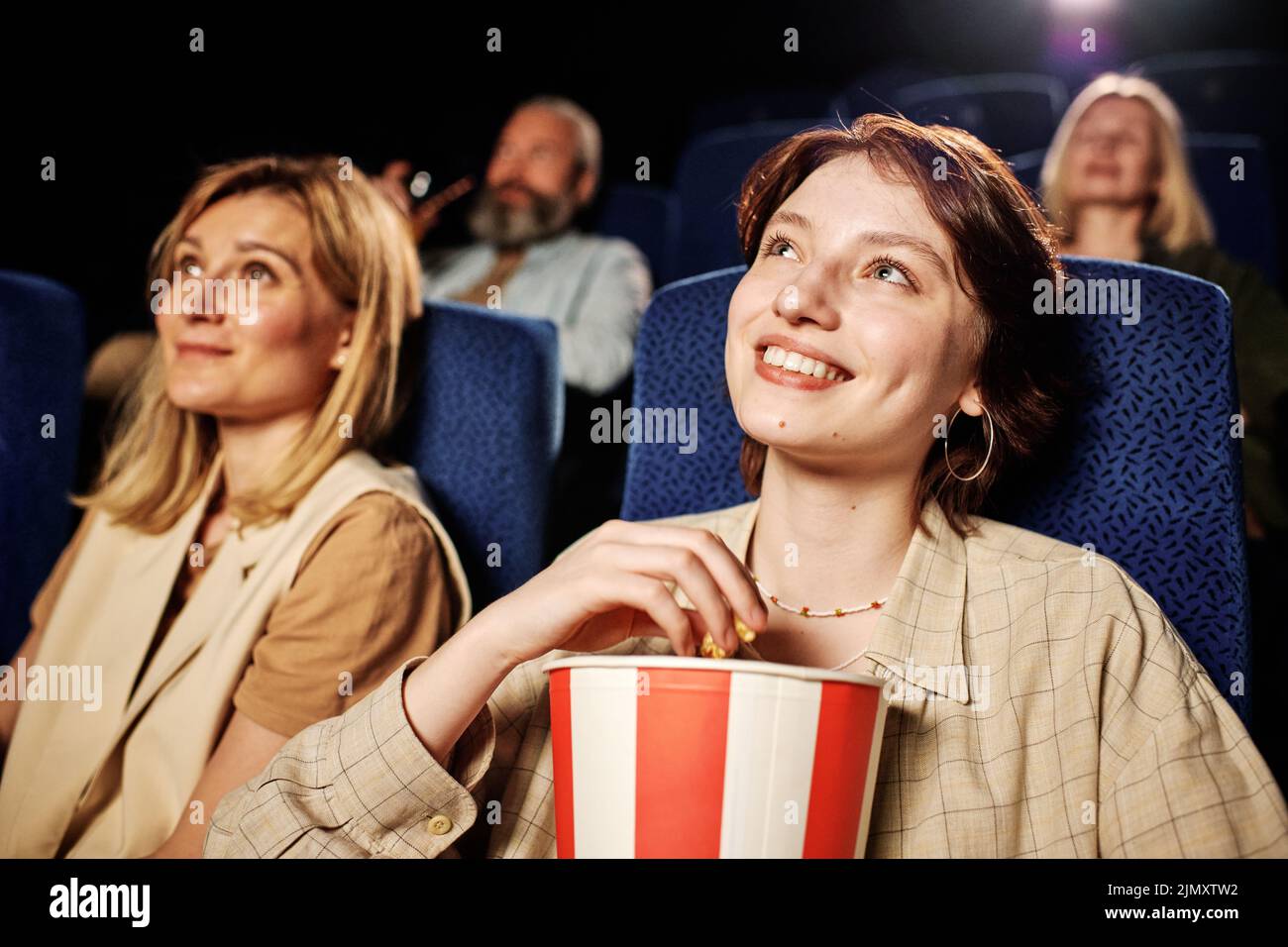 Retrato de la joven y moderna mujer caucásica gen Z disfrutando de una buena película y palomitas de maíz en el cine Foto de stock