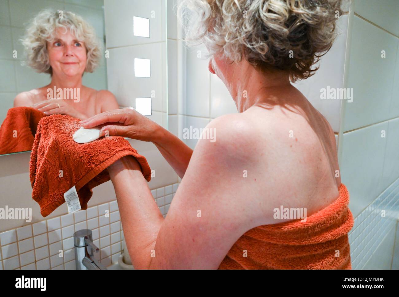 Mujer lavando con franela y jabón en el lavabo del baño para ahorrar agua, ya que algunas zonas de Gran Bretaña están sufriendo escasez de agua Foto de stock