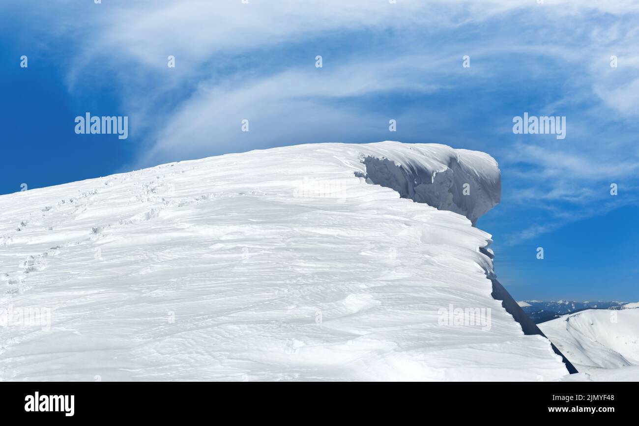 Cima de montaña de invierno con gorro de nieve con diseño de hada y huella humana en las laderas nevadas de la montaña. Foto de stock
